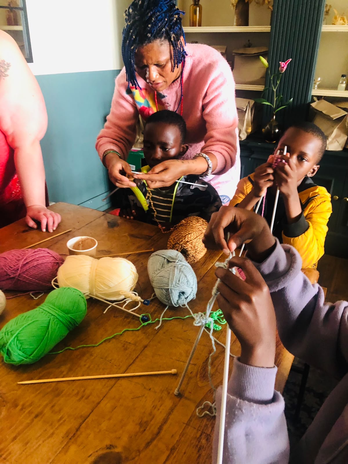 Children learn knitting with an adult using colorful wool