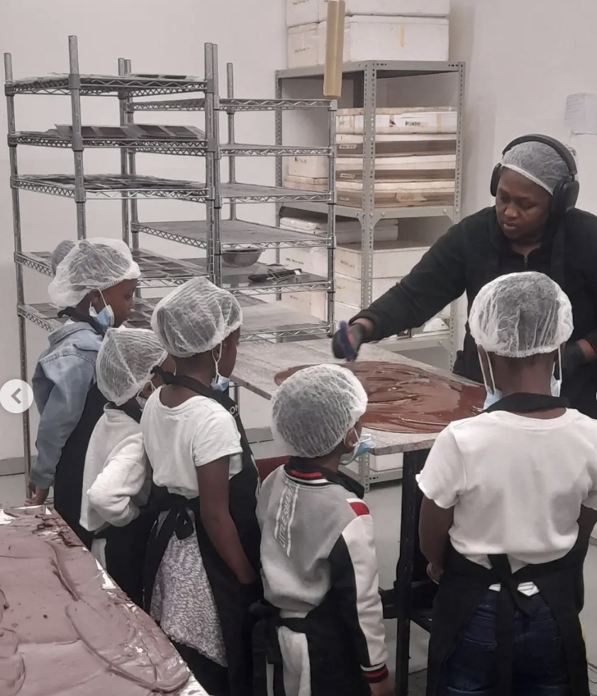 A chocolate maker demonstrating the craft to children