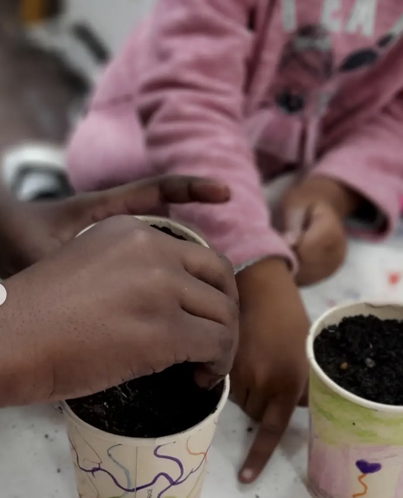 A child planting seeds in a decorated pot